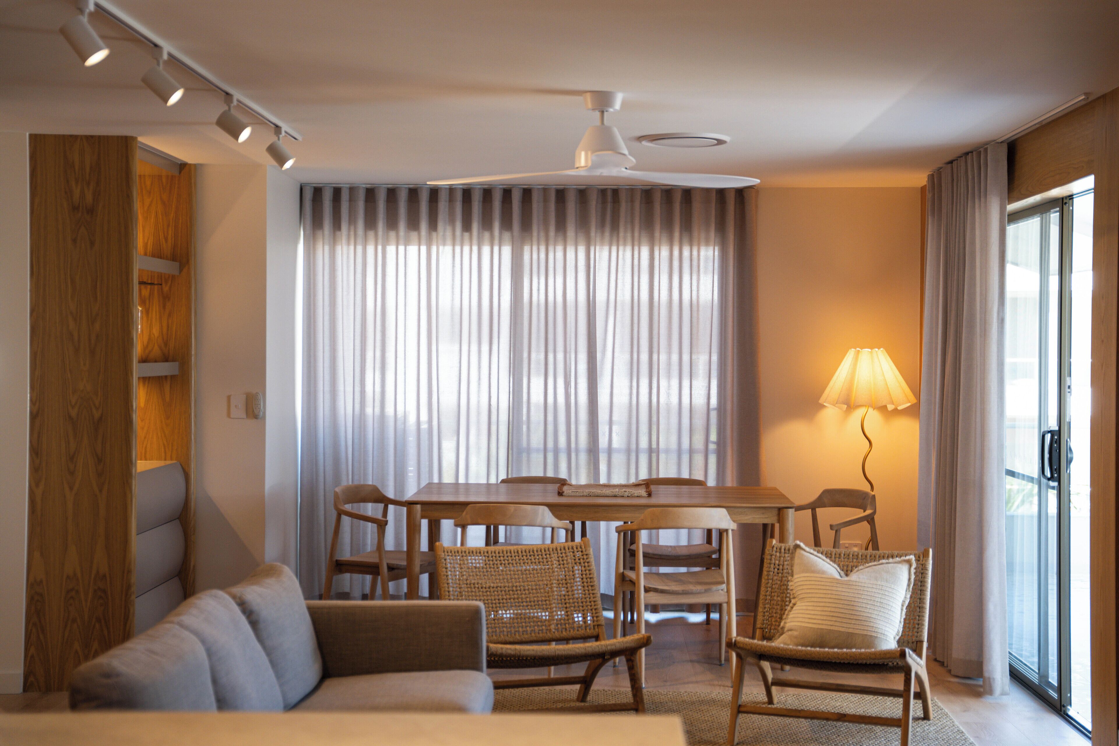 A modern hotel room with a dining area, a sofa, and a lamp.