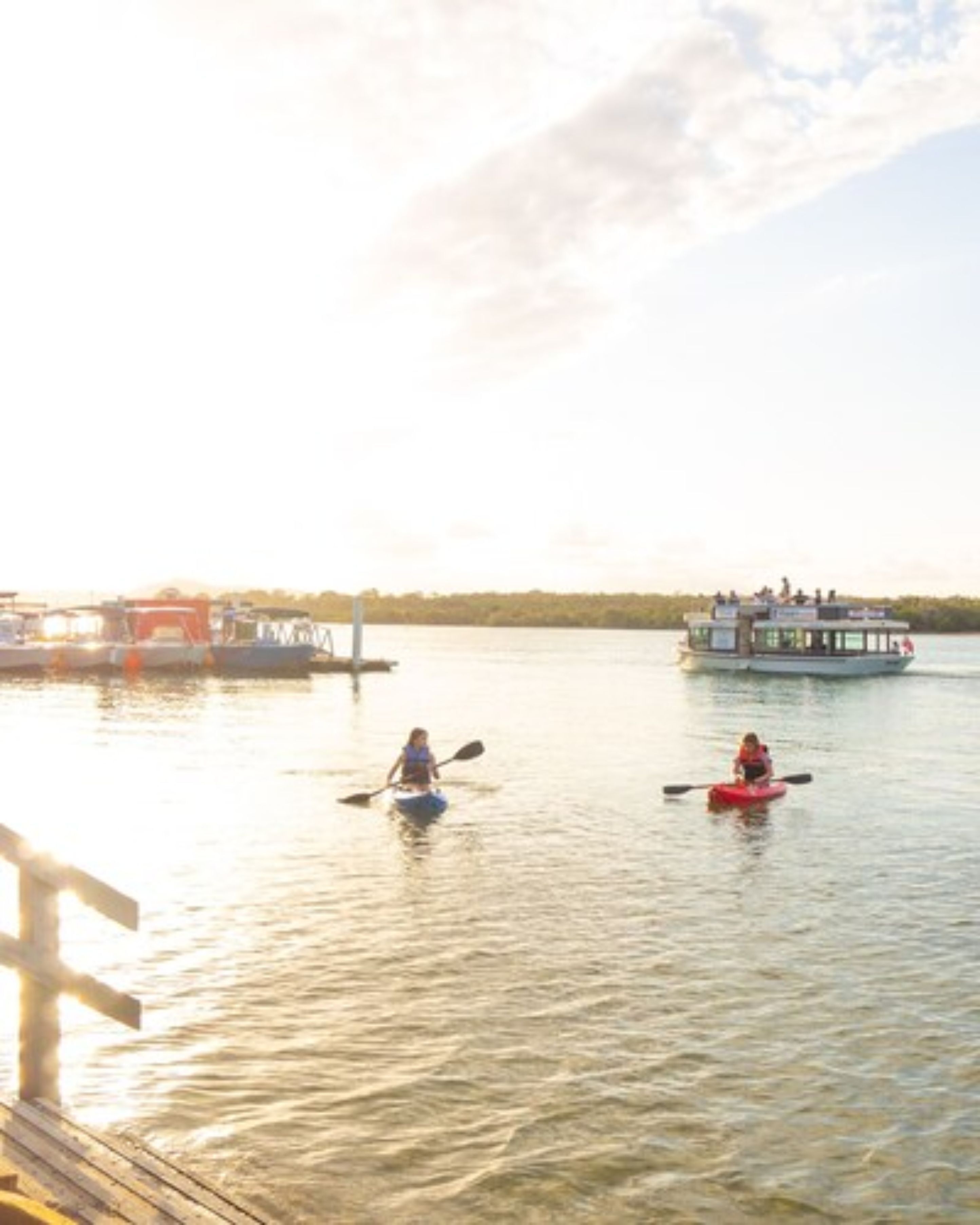 A calm river with kayaks and a boat docked at the pier.