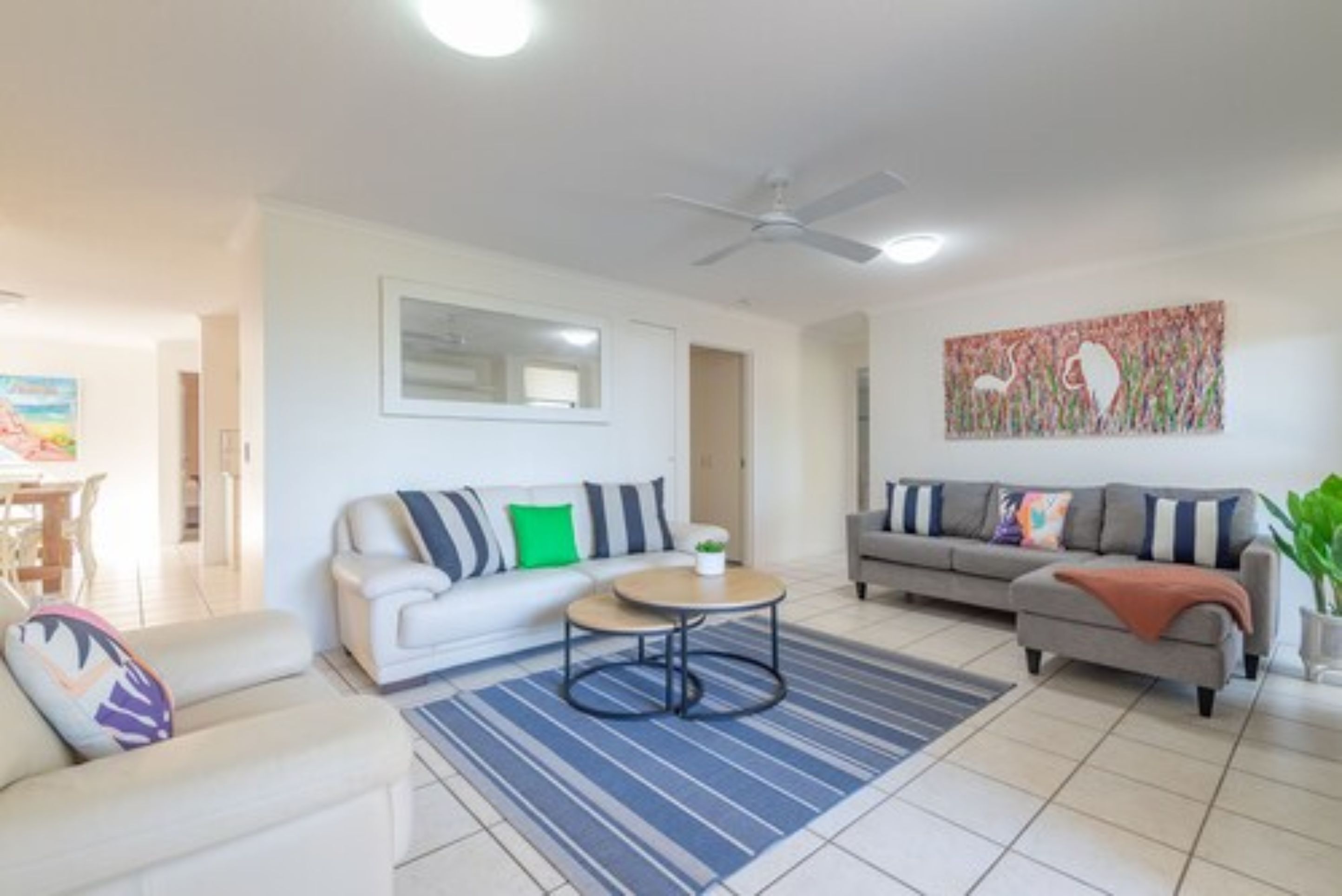 A modern living room with two sofas, a coffee table, and a ceiling fan.