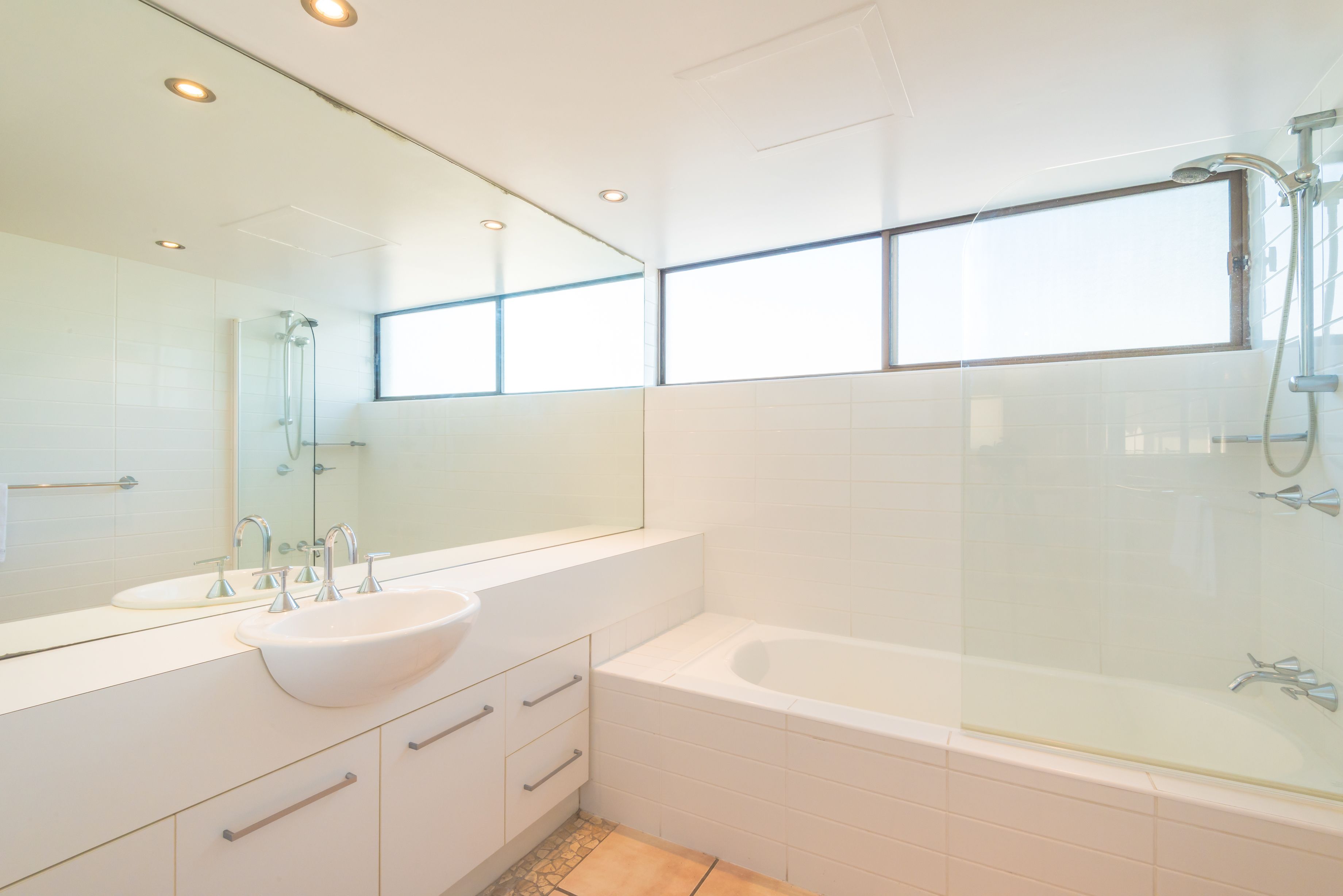 Une salle de bain moderne avec un grand miroir, un lavabo blanc, une baignoire et une douche.