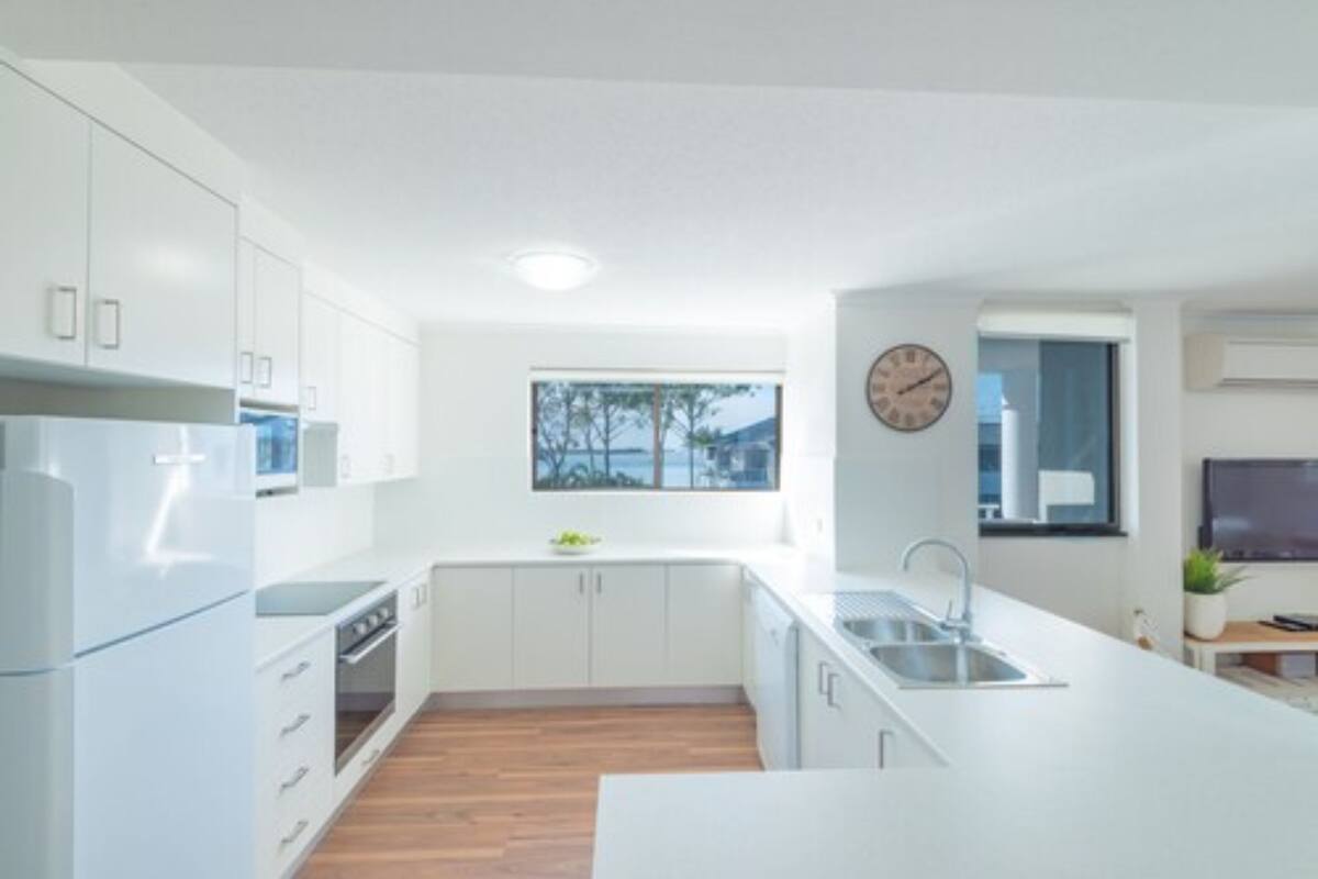 A modern kitchen with white cabinetry, a built-in oven, and a large island with a sink.