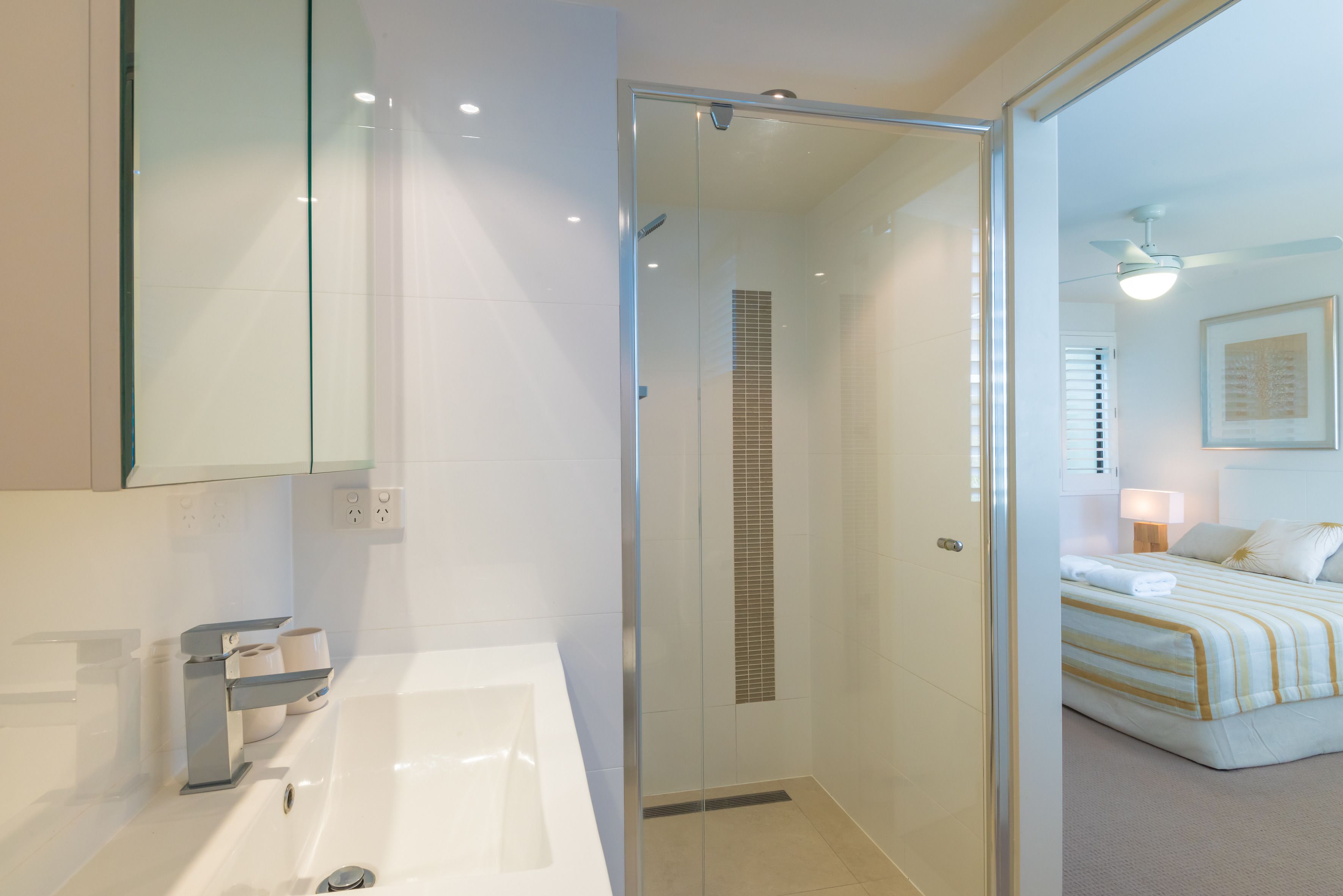 Un baño moderno con cabina de ducha de vidrio, una bañera y cabezal de ducha visible.