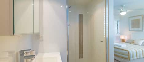 Un baño moderno con cabina de ducha de vidrio, una bañera y cabezal de ducha visible.