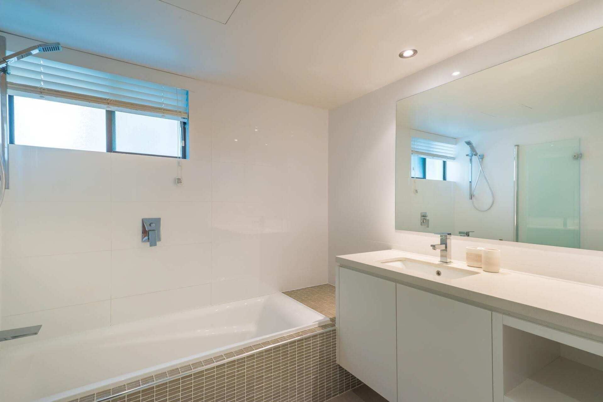 Une salle de bain moderne avec un grand miroir, une baignoire et une douche.