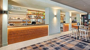Un área de bar moderna con mostrador de ladrillo, taburetes y alfombra estampada.