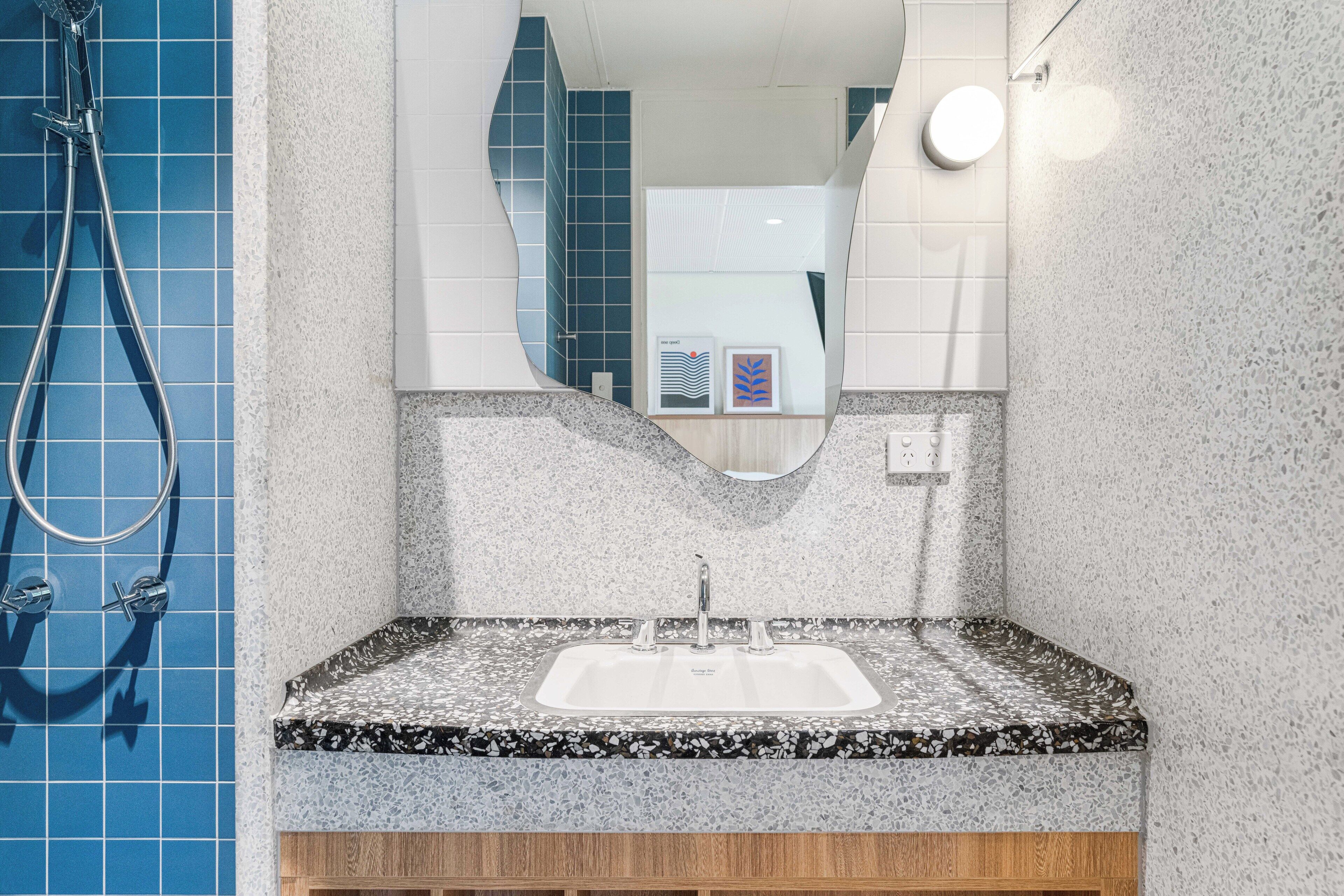 A bathroom with a sink, mirror, and shower.