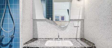 Une salle de bain avec un lavabo, un miroir et une douche.