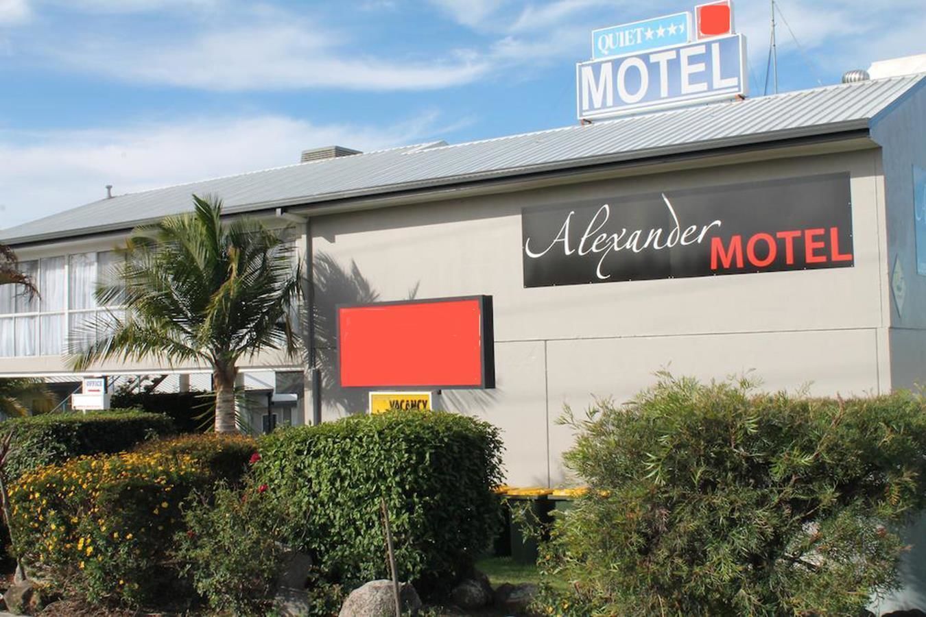 Um motel chamado 'Alexander Motel' com uma placa 'Tranquilo' acima da entrada.