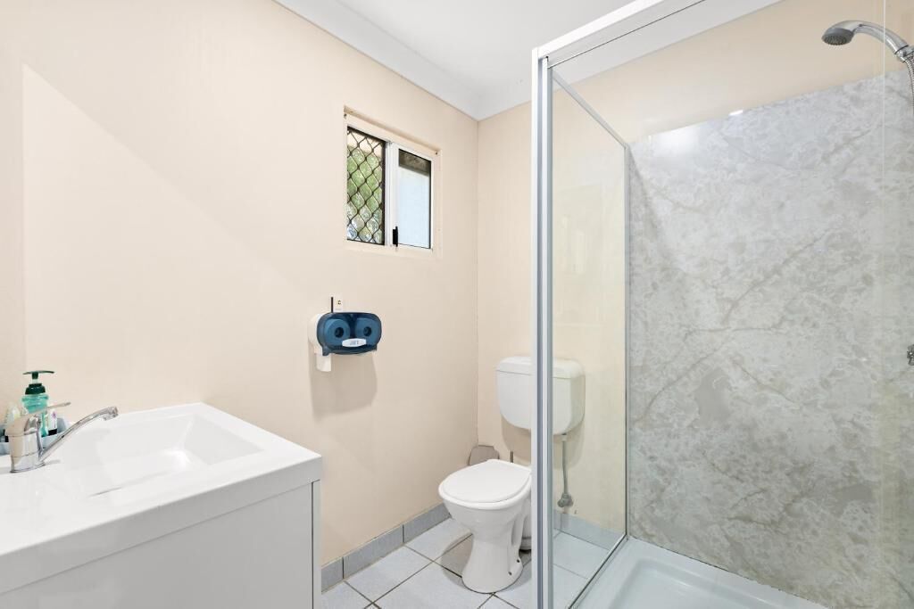 A bathroom with a white sink, toilet, and glass-enclosed shower.