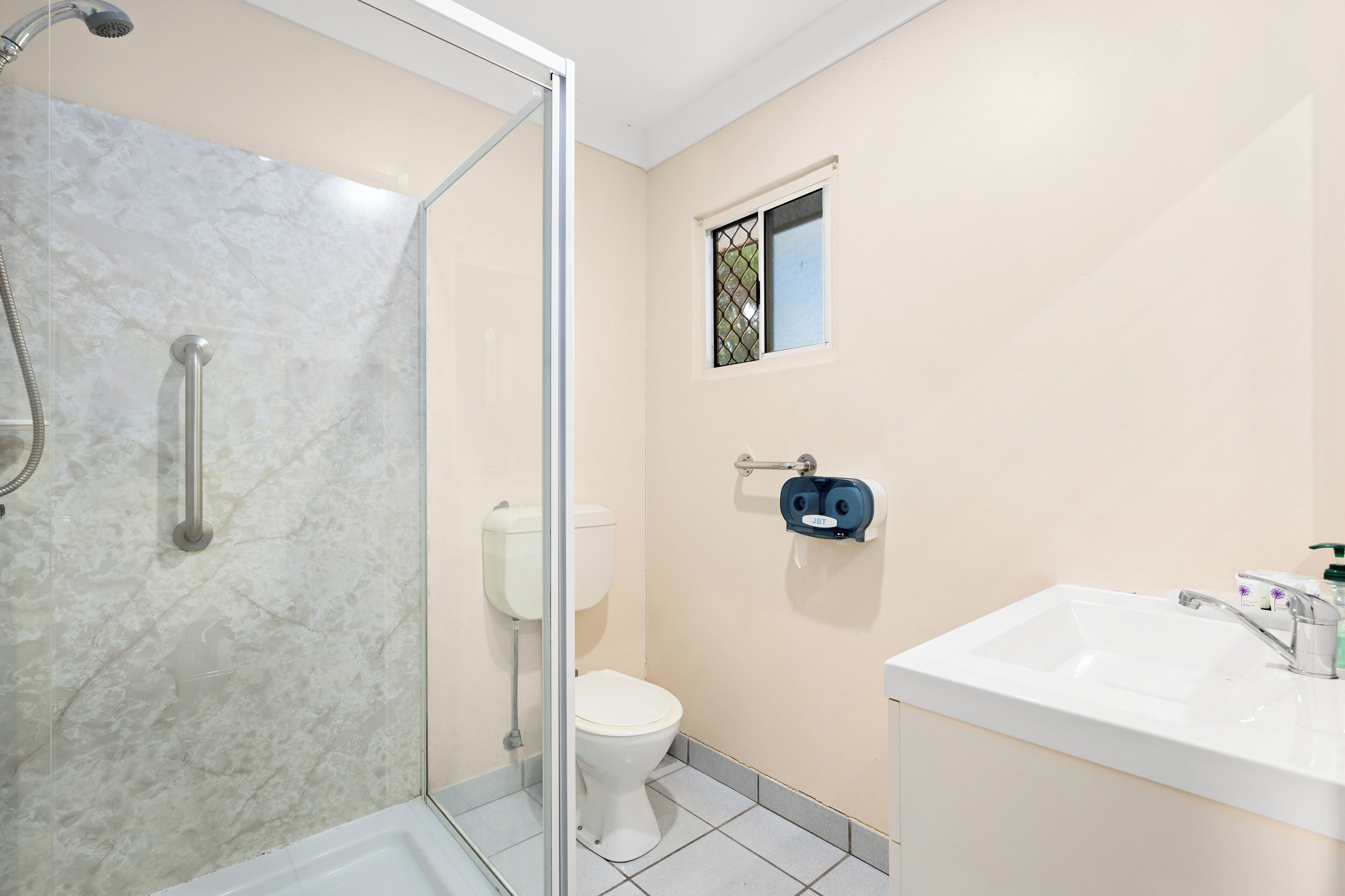 A bathroom with a glass-enclosed shower, a toilet, and a sink with a mirror.