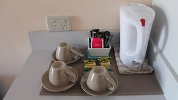 Un desayuno con dos tazas, una jarra y algunos condimentos sobre una bandeja.