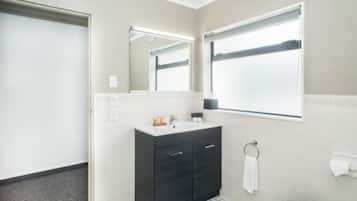 A bathroom with a dark vanity, a mirror, a towel ring, and a toilet paper holder.