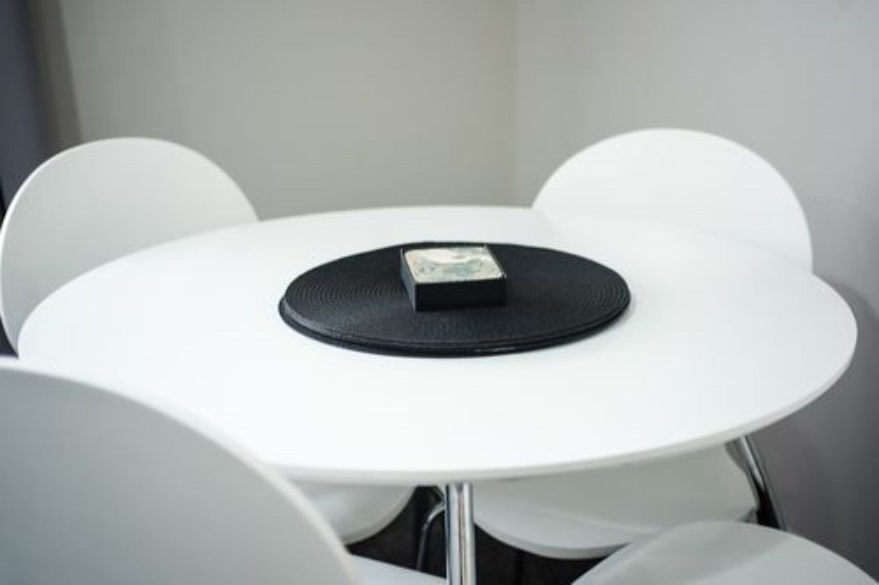 Ein weißer runder Tisch mit schwarzer Unterlage und einem kleinen schwarzen Gegenstand darauf.