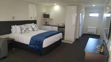 Habitación de hotel con cama, escritorio, microondas, lavamanos y ventana.