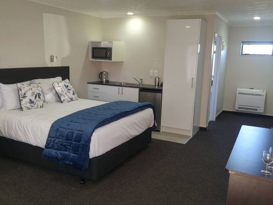 Habitación de hotel con cama, escritorio, microondas, lavamanos y ventana.