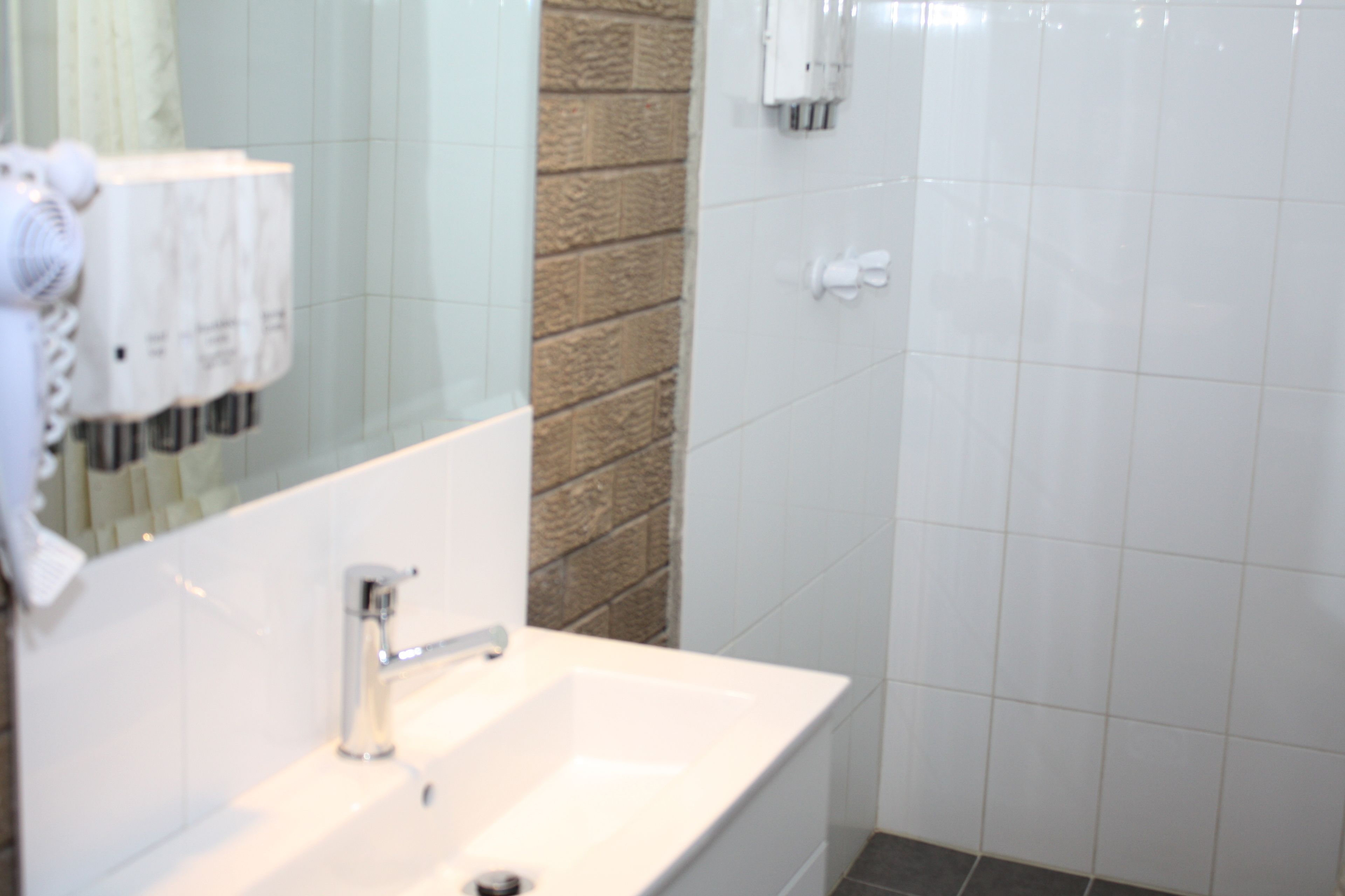 Un baño con lavamanos blanco, un espejo y un perchero para toallas.