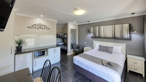 A modern hotel room with a bed, bedside table, and a small desk area with a chair.