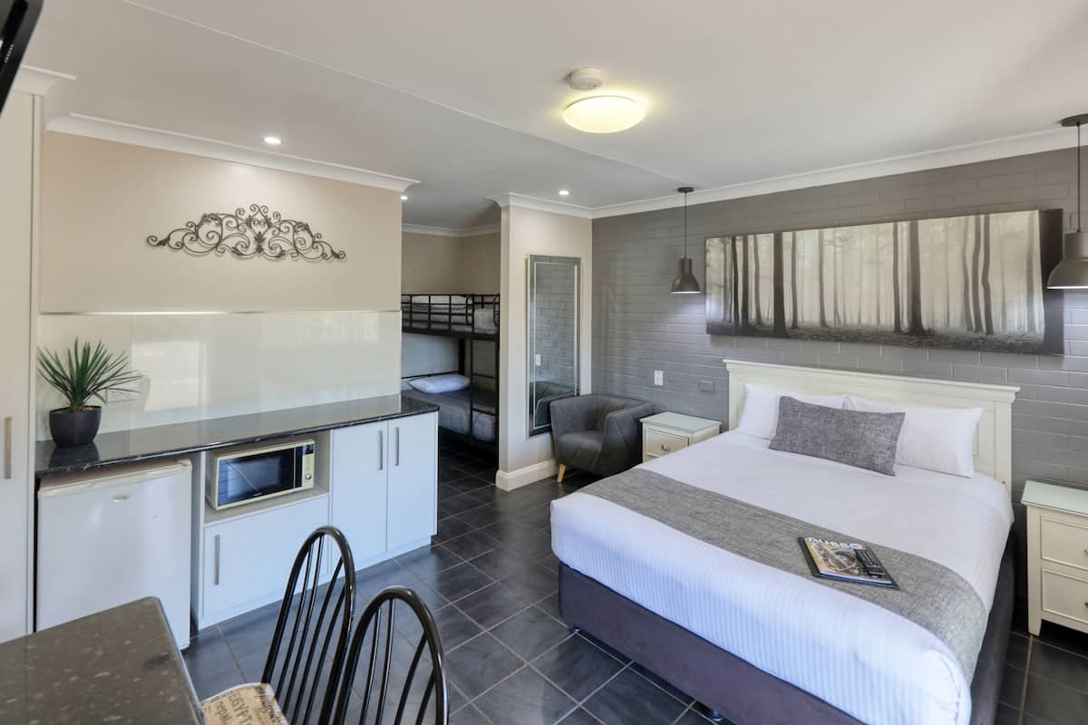 A modern hotel room with a bed, bedside table, and a small desk area with a chair.