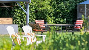 An outdoor patio with a table and chairs, surrounded by lush greenery.