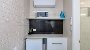 A compact kitchen with a microwave, a small refrigerator, and a potted plant.