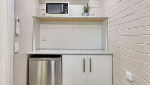 A compact kitchen with a microwave, a small plant, and a stainless steel dishwasher.