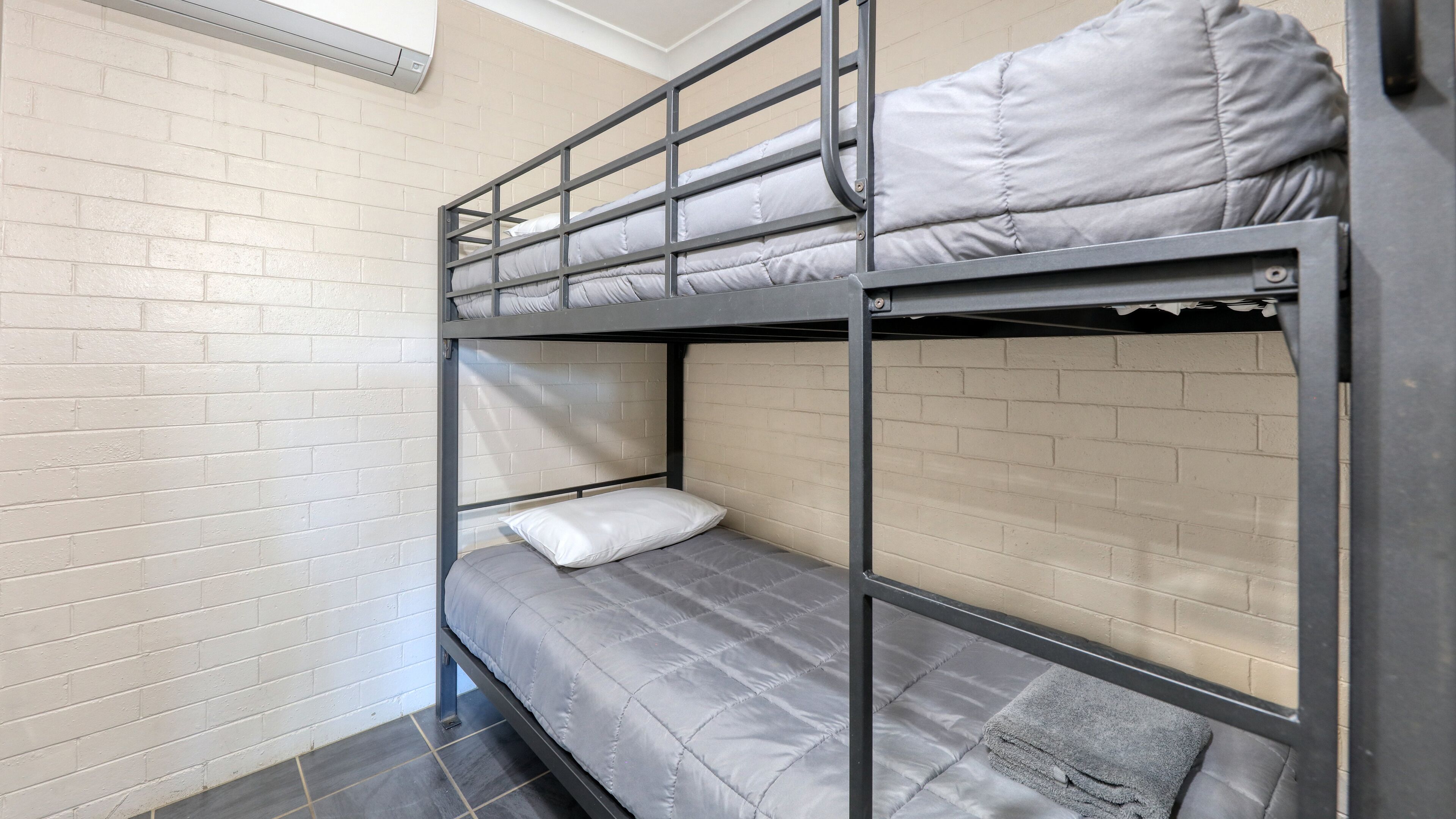 A bunk bed room with white brick walls, a window, and a door.