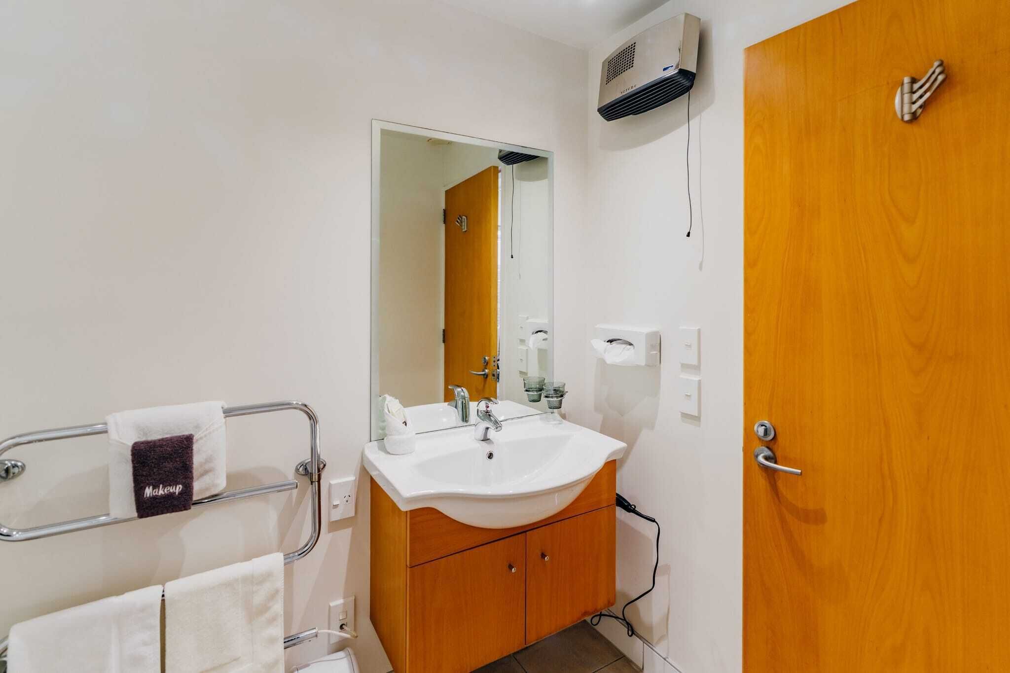 A bathroom with a sink, mirror, towel rack, and wooden cabinet.
