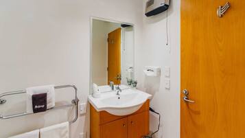 A bathroom with a sink, mirror, towel rack, and wooden cabinet.