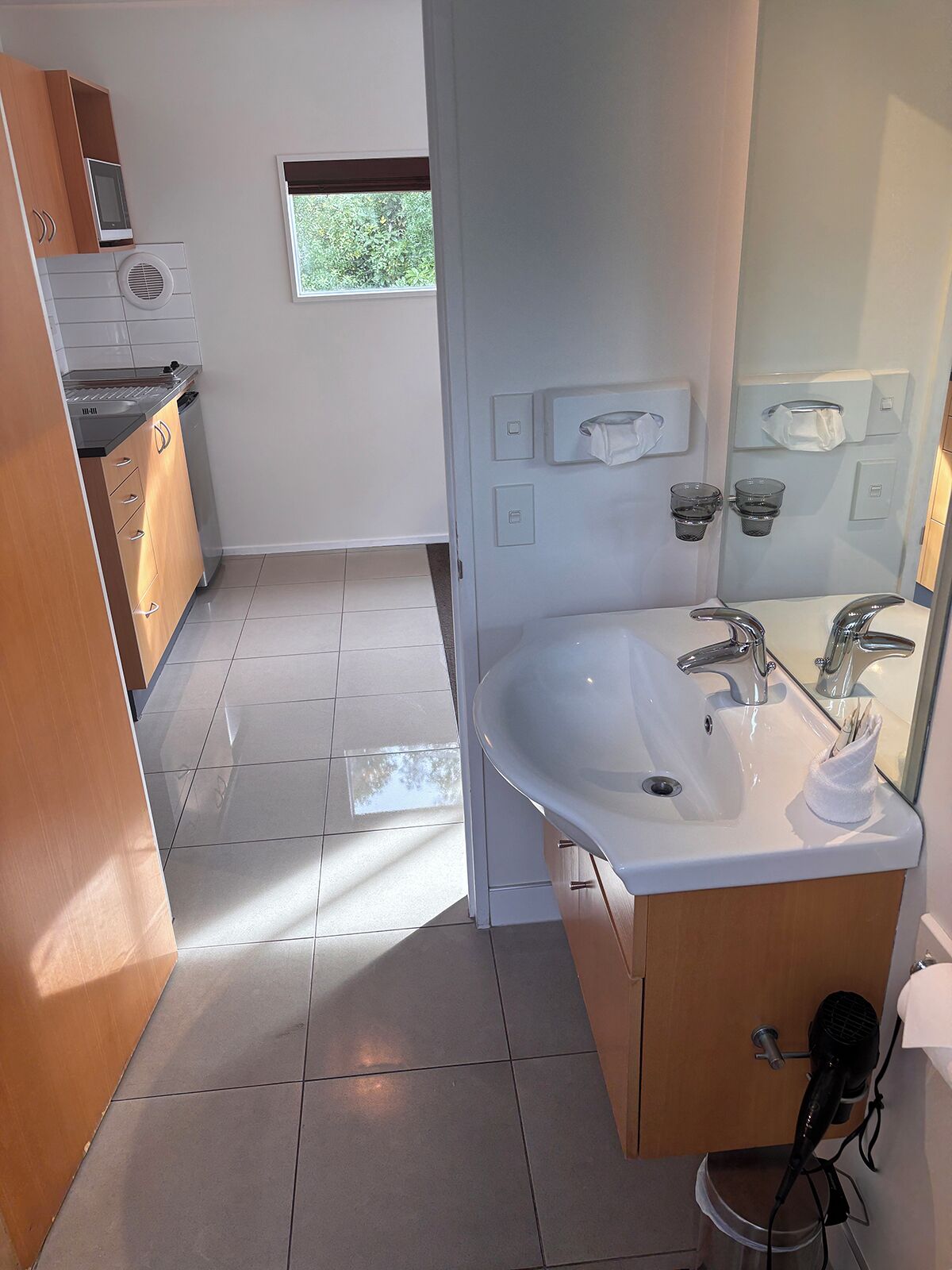 A modern bathroom with a large sink, a mirror, and a hairdryer.