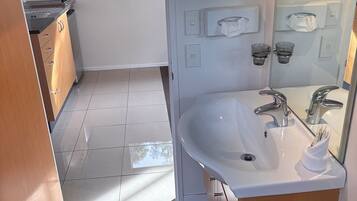 A modern bathroom with a large sink, a mirror, and a hairdryer.