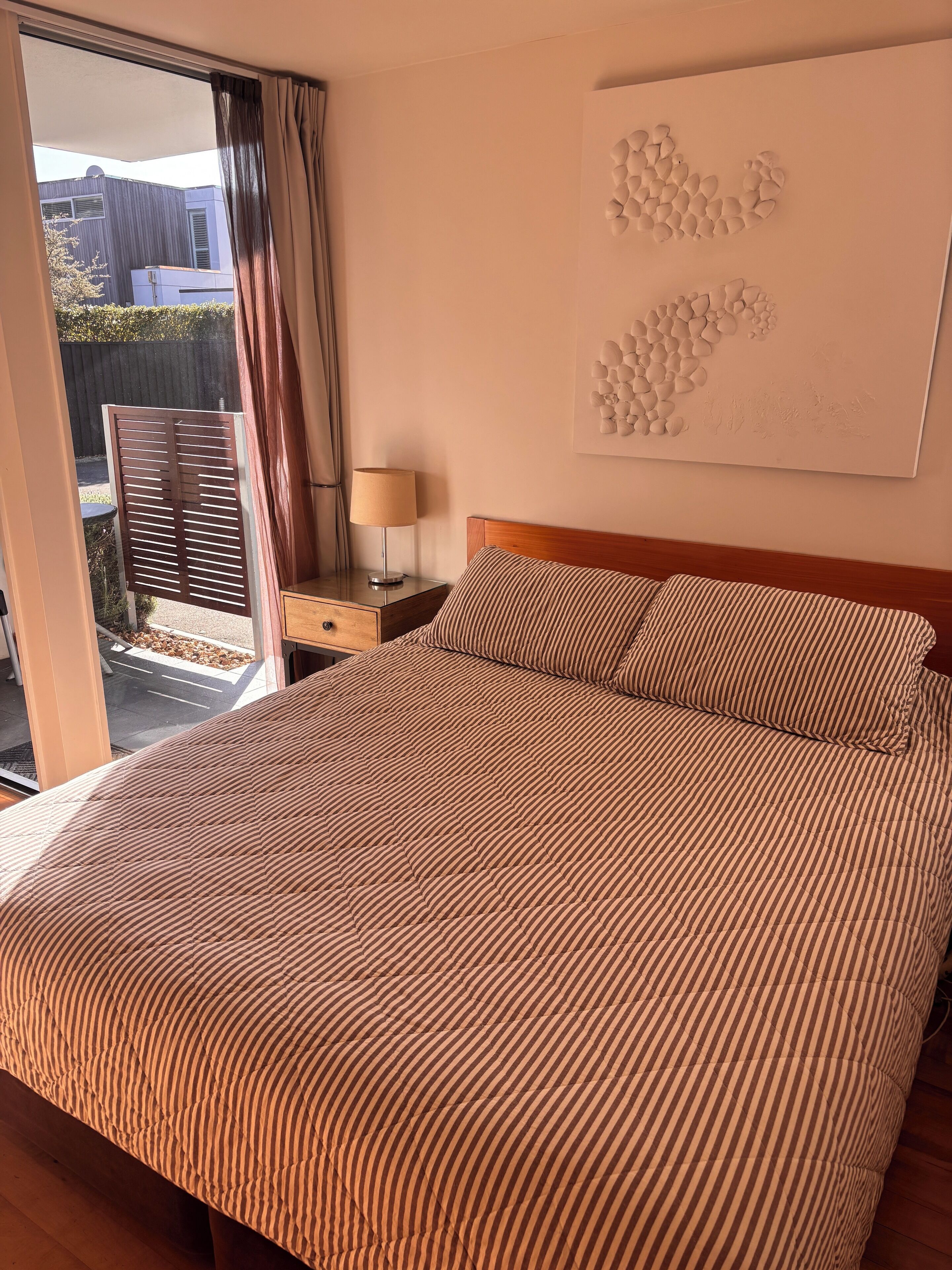 Et hotelværelse med en stor seng, et sengebord, en lampe og udsigt ud