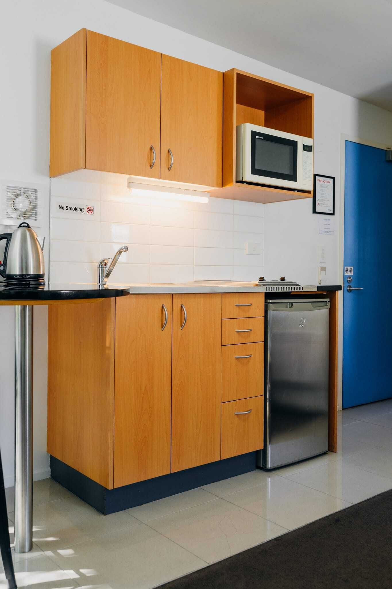 A modern kitchen with wooden cabinets, a stainless steel refrigerator, and a microwave.