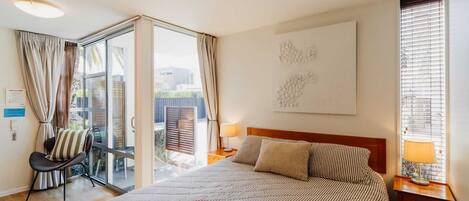 Habitación de hotel con una cama grande, una silla, un escritorio y vistas al exterior.