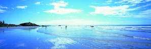 A beach with clear blue water, a sandy shore, and a few people walking. - Sumner Bay Motel & Apartments (Christchurch)