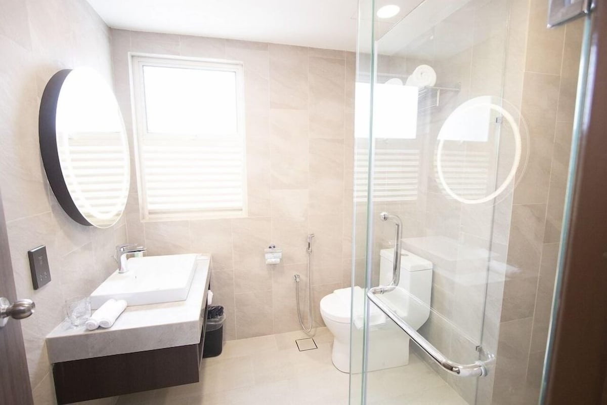 A modern bathroom with a glass shower enclosure, a sink with a mirror, and a toilet.