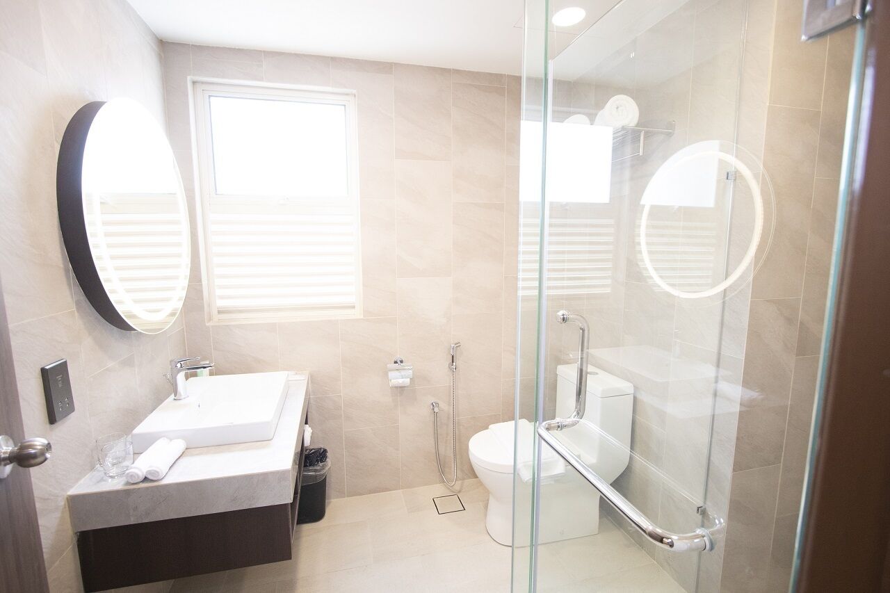 A modern bathroom with a glass-enclosed shower, a white sink, and a toilet.