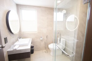 Un baño moderno con ducha envuelta en cristal, un lavabo blanco y un inodoro.