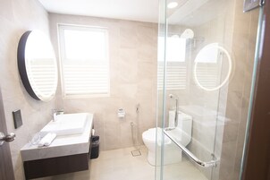 A modern bathroom with a glass-enclosed shower, a white sink, and a toilet.