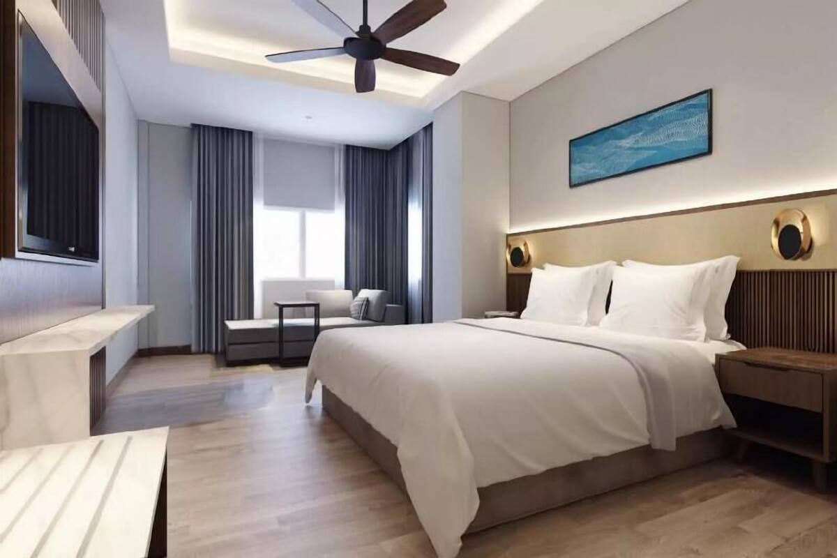 Una habitación de hotel moderna con una cama grande, un ventilador de techo, un escritorio y una ventana con cortinas.
