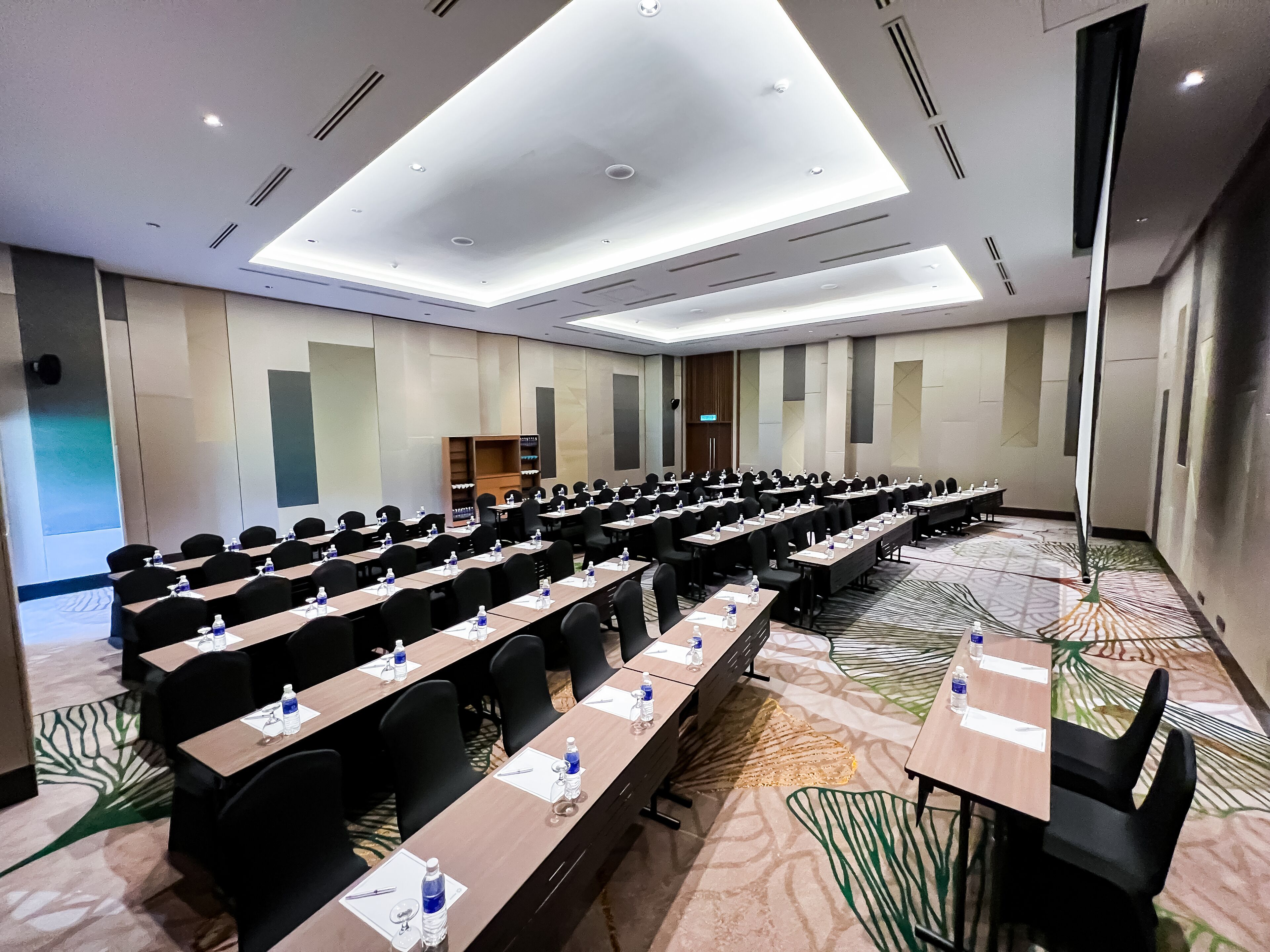 A conference room with rows of tables and chairs, equipped with water bottles and nameplates.