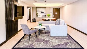Uma sala de estar moderna com um sofá, duas poltronas, uma mesa de centro e uma TV fixada na parede.
