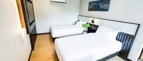 A modern hotel room with a large bed, a small bedside table, an air conditioning unit, and a framed artwork on the wall.