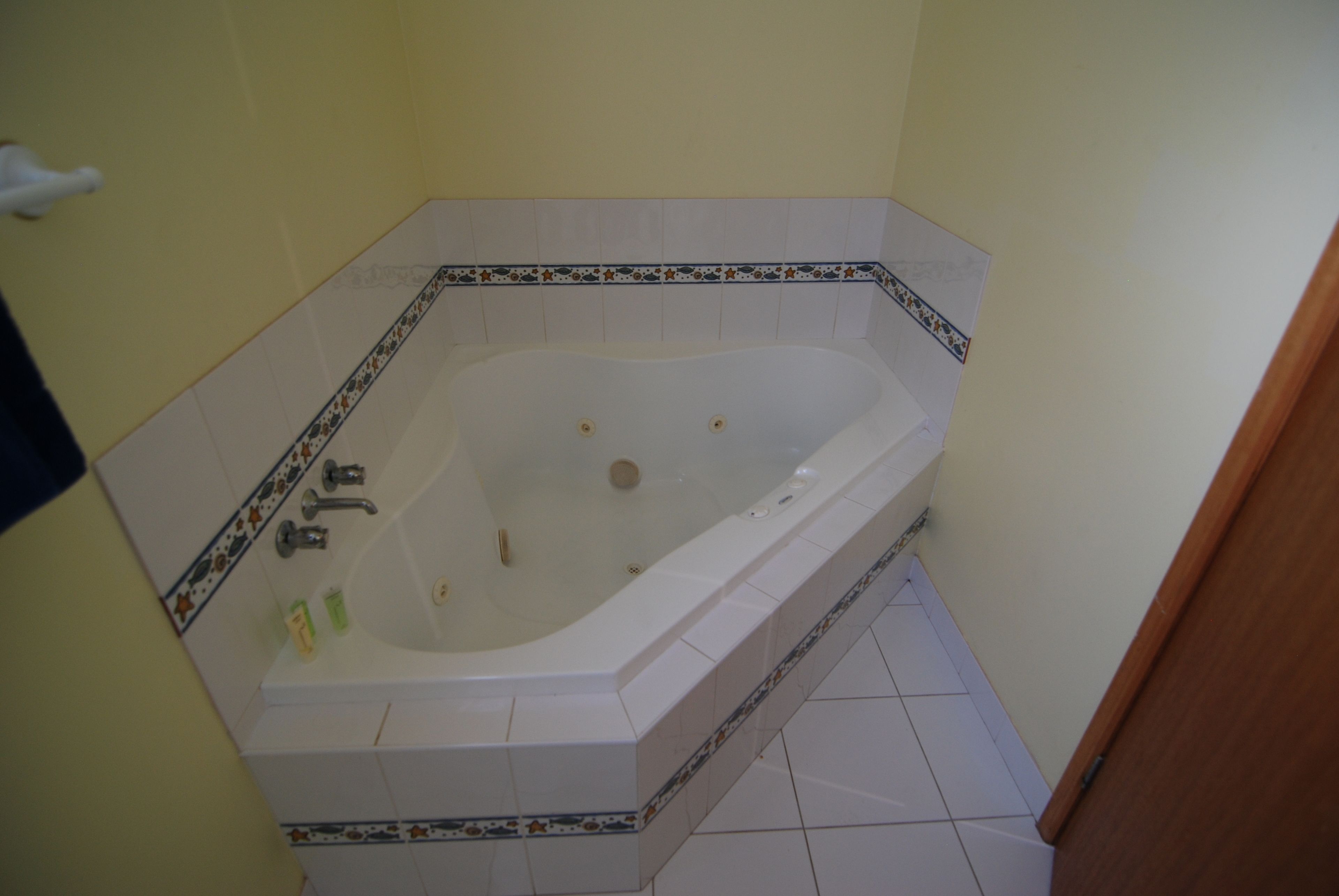 A bathroom with a freestanding bathtub, tiled walls, and a wooden door.
