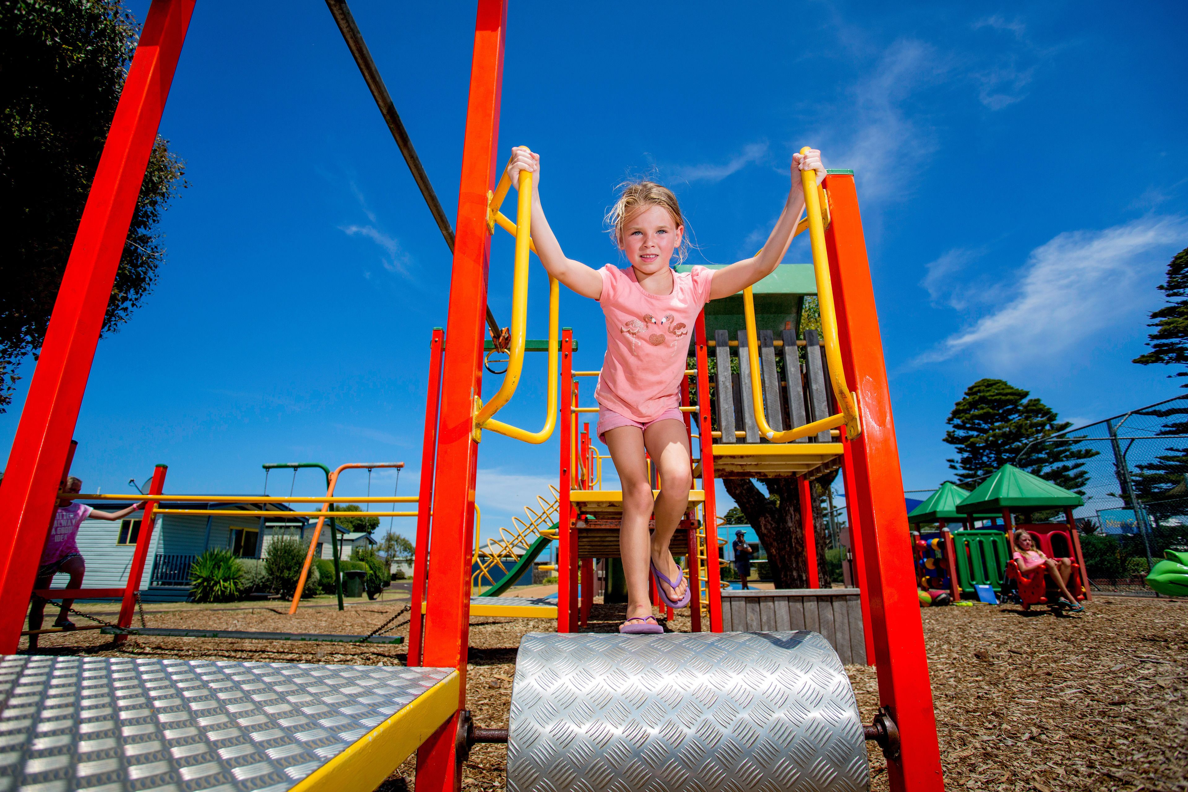 A child on a playground structure with a metal slide and a wooden platform.
