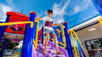 Children can play on the playground with a slide, climbing elements, and play area.