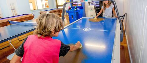 A pool table in a room with arcade games and a pool table in the background.
