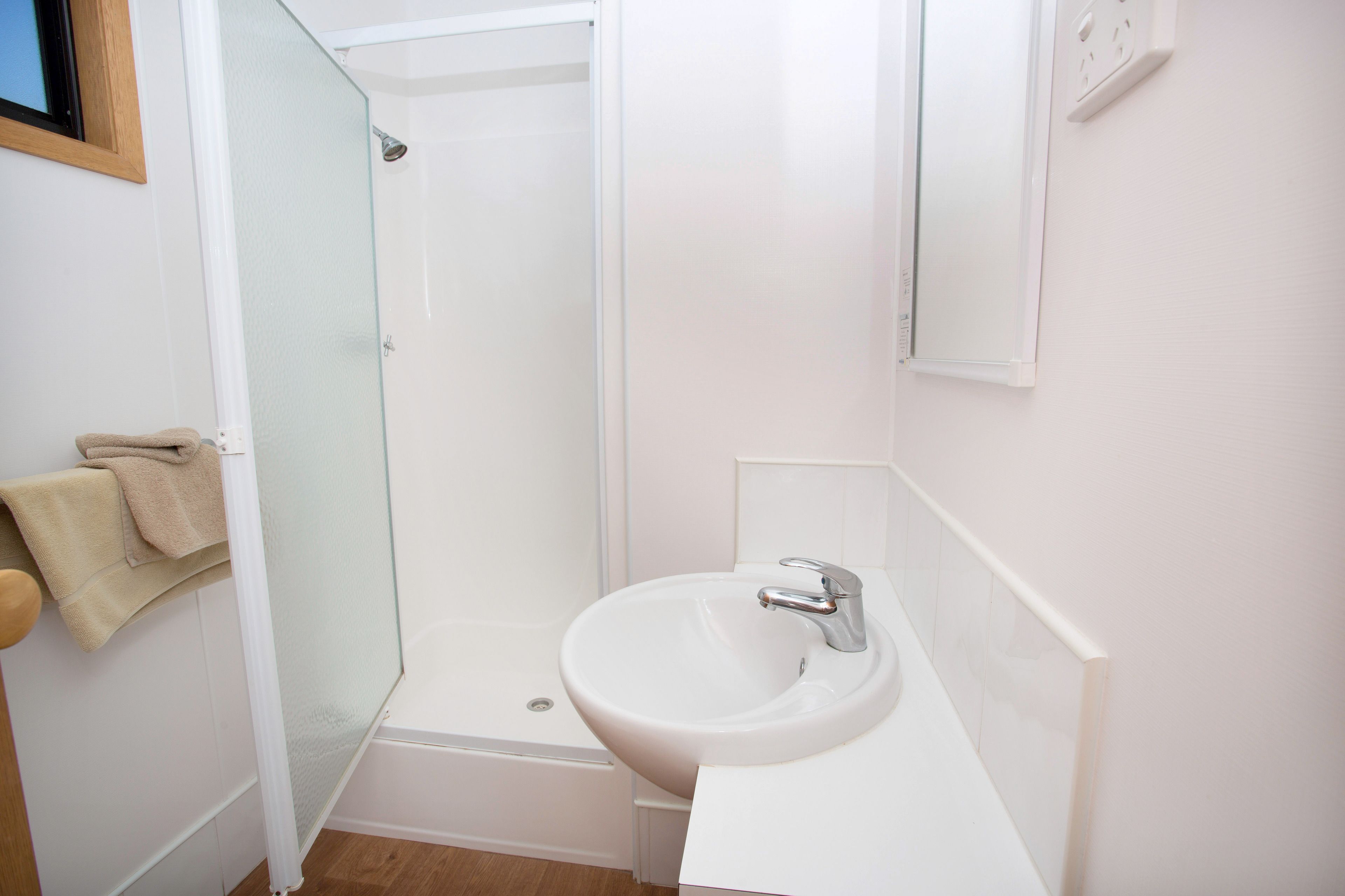 Une salle de bain avec une douche à parois de verre, un lavabo blanc et un miroir au-dessus du lavabo.