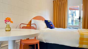 A hotel room with a bed, a table with a vase of flowers, and a chair.