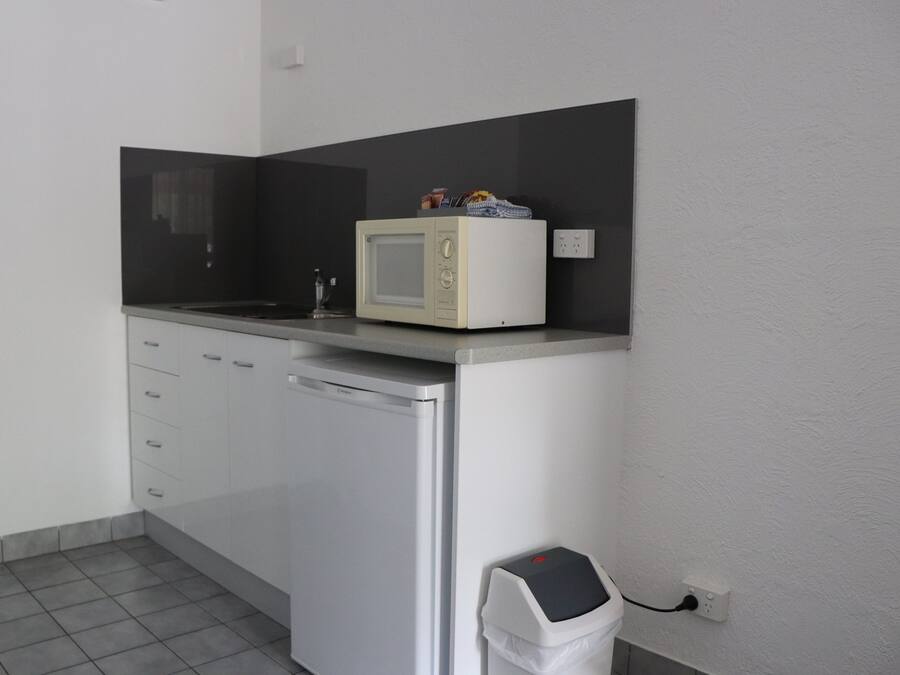 Une petite cuisine équipée d’un four à micro-ondes, d’un petit évier et d’une poubelle.