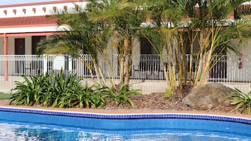 Una piscina al aire libre, sombrillas, sillones reclinables de piscina